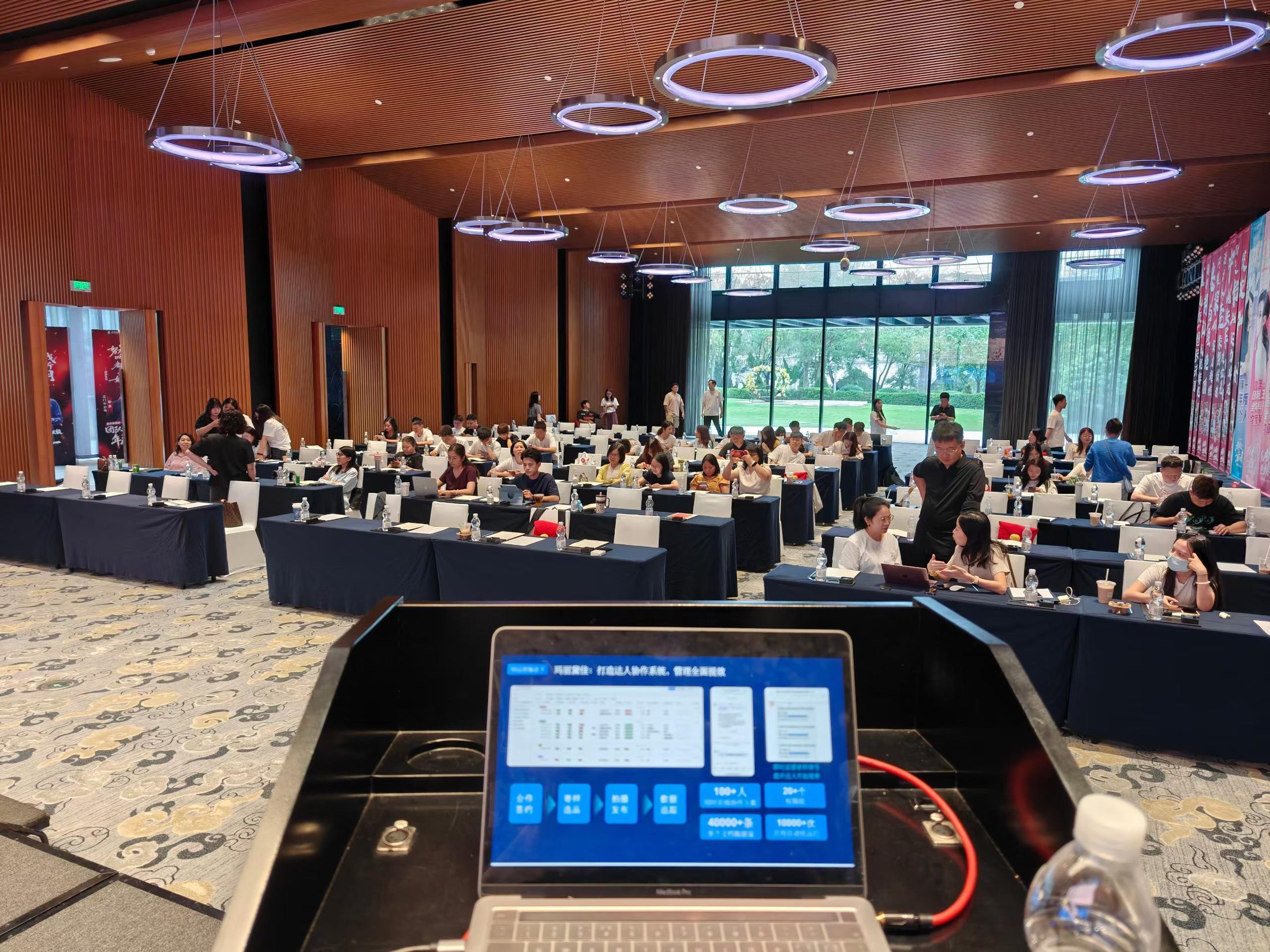 管理层AI工作坊现场，讲台上的电脑正在演示AI工作流